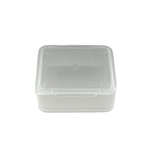 May include: A clear plastic square storage box with a hinged lid. The box has four small circular indents on the lid and bottom.