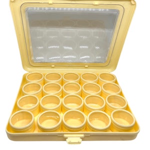 May include: A cream-coloured plastic storage box with a clear lid. The box has 24 small, clear containers inside.