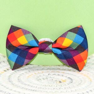 May include: A colorful bow tie with a checkered pattern in shades of red, yellow, blue, and black.
