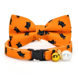 May include: Orange cat-print breakaway cat collar with a matching bow tie and a gold bell and pearl charm.