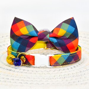May include: A yellow cat collar with a rainbow plaid bow tie and a blue jewel bell charm.