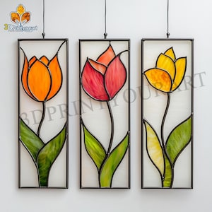 May include: Three stained glass panels featuring tulip designs. Each panel has a black metal frame and a hanging wire. The tulips are in shades of orange, red, and yellow, with green leaves. The background is a translucent white.