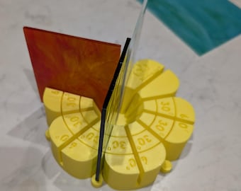 May include: A yellow plastic tool with markings in degrees, used for aligning glass pieces. Two pieces of glass are placed in the tool, one red and one clear.