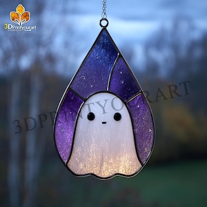 May include: Stained glass ghost suncatcher with a purple and blue background. The ghost has a white body and black eyes. The suncatcher is hanging from a chain. The text "3DPrintyourart" is visible.