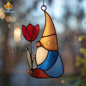 Puede incluir: Un gnomo de vidriera sosteniendo un tulipán rojo. El gnomo tiene un sombrero amarillo, barba blanca y ropa azul. El arte de la vidriera cuelga de una cadena. El texto "3DPrintyourart" es visible.