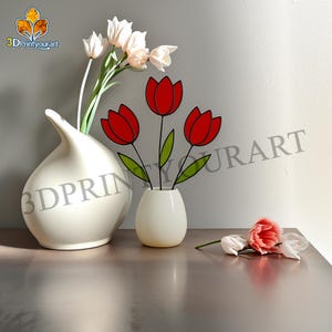 Op de afbeelding: Een stilleven met twee witte keramische vazen. Eén vaas bevat kunsttulpen, de andere rode tulpuitsparingen. Een enkele roze bloem en witte bloemen zijn ook aanwezig. De achtergrond is een neutraal grijs.