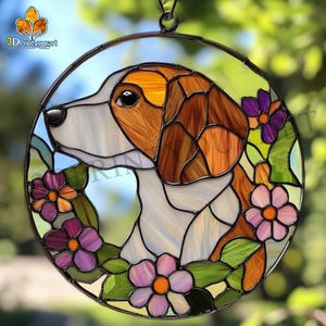 Könnte beinhalten: Ein Buntglas-Sonnenfänger mit einem braunen und weißen Hund mit braunen Ohren, umgeben von lila und rosa Blumen mit grünen Blättern. Der Sonnenfänger ist rund und hat einen Metallrahmen.