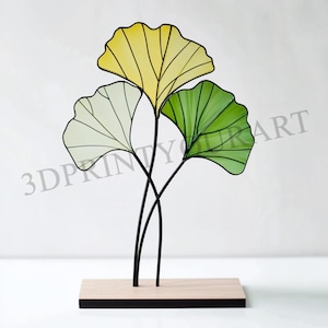 May include: A decorative sculpture of three ginkgo leaves in yellow, green, and white, mounted on a wooden base.