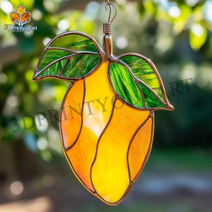 May include: A stained glass mango with green leaves hanging from a copper wire. The mango is yellow and orange with a textured surface.