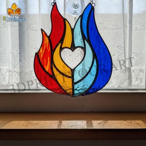 May include: Stained glass art piece in the shape of a flame, featuring red, yellow, and blue sections. A white heart shape is in the center. The text "3DPrintyourart" is visible.