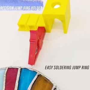 Pode incluir: Um suporte para anéis de salto impresso em 3D vermelho e amarelo, segurando um anel de salto prateado. O texto "PRECISION JUMP RING HOLDER" é visível na imagem. O texto "EASY SOLDERING JUMP RING" também é visível na imagem.
