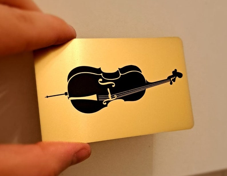 May include: A black silhouette of a cello on a gold background.