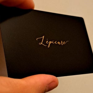May include: A black card with the word 'L'epicure' written in gold lettering.