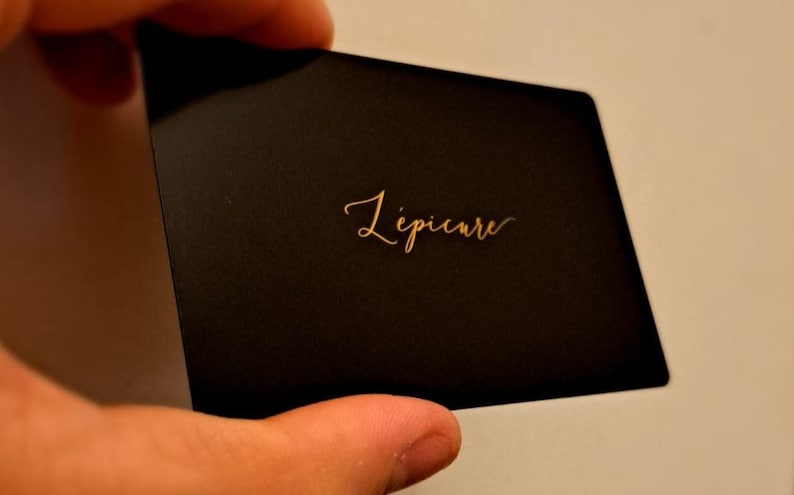 May include: A black card with the word 'L'epicure' written in gold lettering.