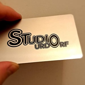 May include: A silver card with black text that reads 'Studio Urdorf'.