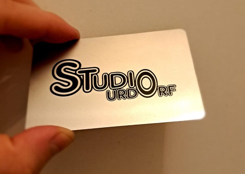 May include: A silver card with black text that reads 'Studio Urdorf'.