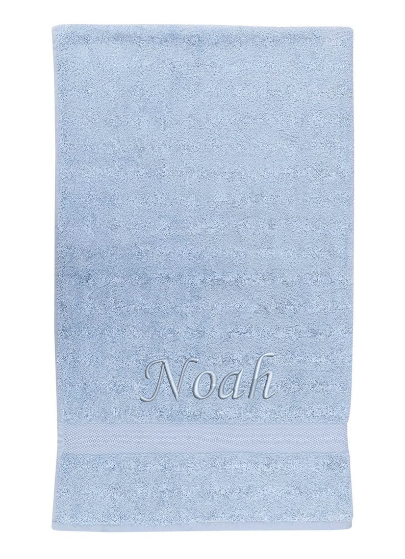 May include: A light blue towel with the name "Noah" embroidered in silver thread.
