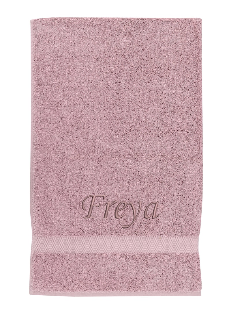 May include: A soft, pink bath towel with the name "Freyja" embroidered in a cursive font.
