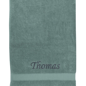 May include: A teal bath towel with the name "Thomas" embroidered in black thread.
