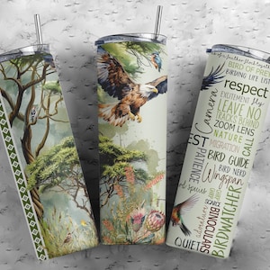 May include: Three stainless steel tumblers with different designs. The first tumbler has a green and brown nature scene with a bird. The second tumbler has a green and brown nature scene with a bird. The third tumbler has a white background with text about birdwatching. The text includes "Bird of Prey", "Respect", "Leave No Tracks Behind", "Zoom Lens", "Nature", "Migration", "Bird Guide", "Wingspan", "Birdwatcher", "Binoculars", and "Quiet".