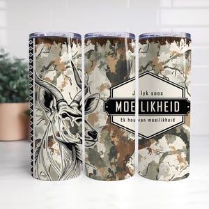 May include: A stainless steel tumbler with a camouflage pattern and a black and white illustration of a kudu. The tumbler has the text "MOE LIKHEID" and "Ek hou van moeilikheid" in a black and white label.