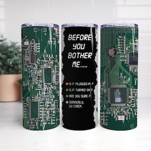 May include: A set of three stainless steel insulated tumblers. The tumblers feature a green circuit board design. One tumbler has the text "BEFORE YOU BOTHER ME....." with troubleshooting questions. The tumblers are designed to keep drinks cold or hot.