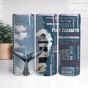 Puede incluir: Tres vasos de viaje de acero inoxidable con temática costera. Uno presenta una cola de ballena, otro un faro y el tercero texto sobre Port Elizabeth. Los vasos tienen una combinación de colores azul y blanco.