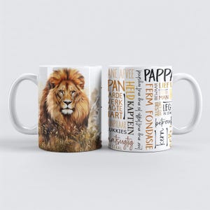 May include: Two white ceramic mugs. One mug features a detailed illustration of a lion with a golden mane. The other mug has text in various fonts and colors. The text includes words like "PAPP", "HELD KAPTEIN", and "FERM FONDASIE".