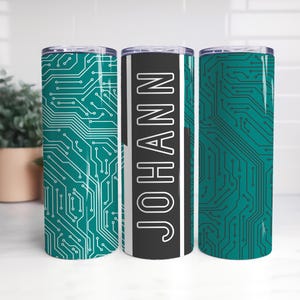 Könnte beinhalten: Drei Edelstahlbecher mit Deckel. Zwei Becher zeigen ein tealfarbenes Leiterplattendesign, während der mittlere Becher den Namen "JOHANN" in Weiß auf einem schwarz-grauen Hintergrund trägt. Die Becher sind zylindrisch.