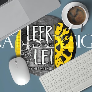May include: A workspace scene with a laptop, keyboard, and mouse. A round mousepad features text and a yellow ruler graphic. A cup of coffee sits nearby. The word "DESIGNS" is visible.