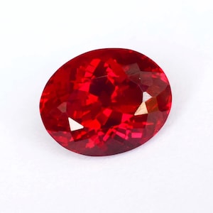May include: A deep red oval-shaped gemstone with a faceted cut.