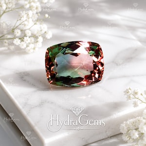 May include: A cushion-cut gemstone displaying a color-changing effect with shifting hues of deep green, soft pink, and warm bronze. The faceted stone features a polished surface that reflects light, creating a multi-dimensional appearance.