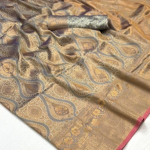 May include: A gold and grey silk saree with a traditional paisley pattern. The saree has a pink border and a silver and gold pallu.