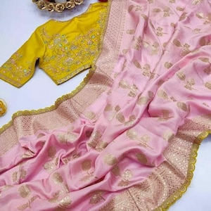 May include: A pink silk saree with gold embroidery and a yellow embroidered blouse. The saree has a gold border with a scalloped edge.
