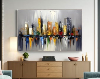 Puede incluir: Pintura abstracta de paisaje urbano con marco plateado. La obra presenta un horizonte con edificios coloridos en amarillo, naranja y azul, reflejados en agua. La pintura está sobre un fondo gris. El texto en la parte inferior dice "ROLLED CANVAS | 100% ORIGINAL | UNFRAMED ART."