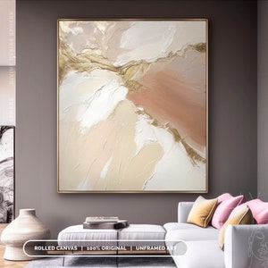 May include: Abstract painting with a gold frame. The artwork features textured brushstrokes in shades of white, beige, and peach, with gold accents. The text at the bottom reads "ROLLED CANVAS | 100% ORIGINAL | UNFRAMED ART".