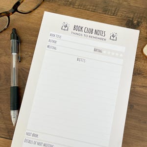 May include: A white paper notepad titled BOOK CLUB NOTES THINGS TO REMEMBER with fields for book title, author, meeting, rating with five stars, a large section for notes, and fields for next book and details of next meeting, accompanied by a pen.