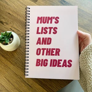 Puede incluir: Una libreta de espiral rosa con el texto "MUM'S LISTS AND OTHER BIG IDEAS" en letras rosas y en negrita.