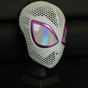 May include: White mask with a perforated pattern, featuring purple-edged eye openings with a holographic effect. The mask is designed with a superhero theme, suitable for cosplay or costume events.
