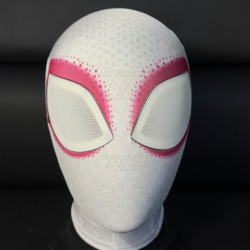 Puede incluir: M&aacute;scara blanca de Spider-Gwen con detalles en rosa alrededor de los ojos. La m&aacute;scara tiene un patr&oacute;n texturizado y cubiertas oculares de malla blanca. La m&aacute;scara est&aacute; dise&ntilde;ada para cubrir toda la cabeza y el cuello.