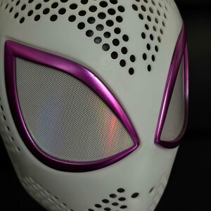 May include: A white mask with a perforated pattern and bright purple eye frames. The eye openings have a mesh material, and the mask has a sleek, modern look. The mask is likely for cosplay or costume use.