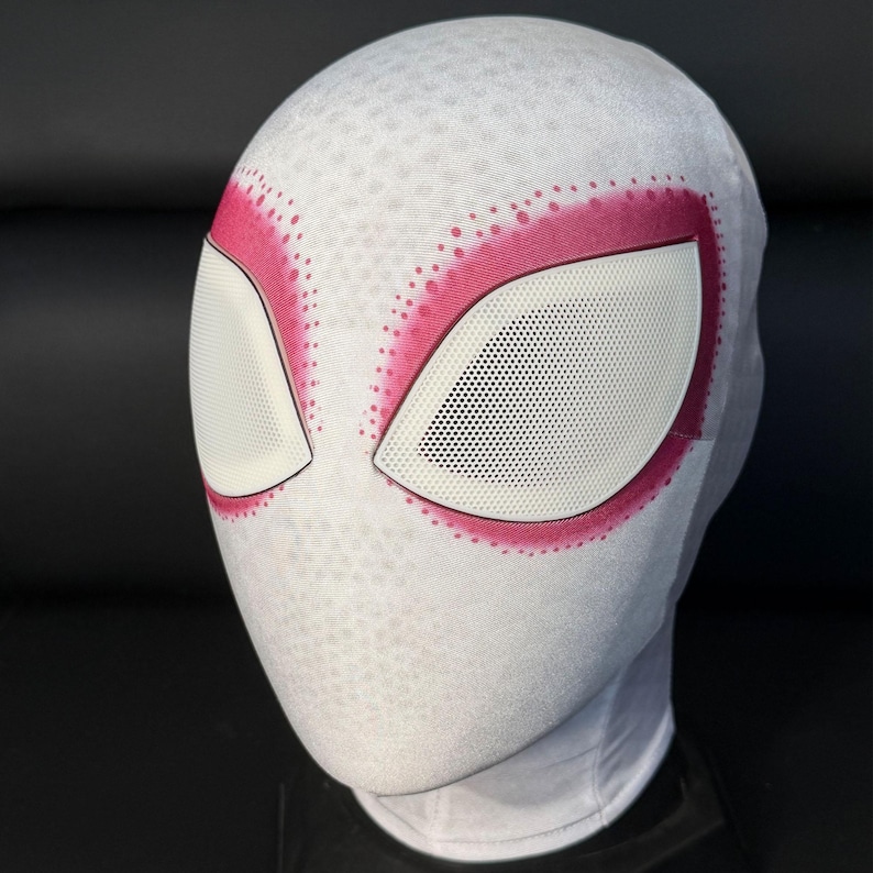 Puede incluir: M&aacute;scara blanca y rosa de Spider-Gwen con grandes aberturas para los ojos blancas delineadas en rosa. La m&aacute;scara tiene un patr&oacute;n texturizado y est&aacute; dise&ntilde;ada para cubrir toda la cabeza y el cuello. Las aberturas de los ojos tienen un material de malla.