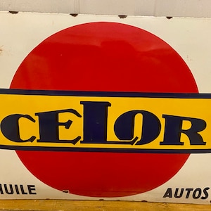 Puede incluir: Un letrero vintage de esmalte con un círculo rojo y la palabra "CELOR" en letras azules sobre un fondo amarillo. El letrero también dice "HUILE" y "AUTOS" en letras negras.