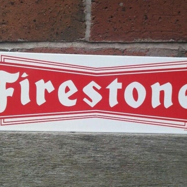 Può includere: Un cartello in metallo bianco con bordo rosso e la parola "Firestone" in lettere bianche.