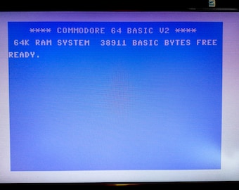 May include: A blue screen with white text that reads "**** COMMODORE 64 BASIC V2 **** 64K RAM SYSTEM 38911 BASIC BYTES FREE READY."