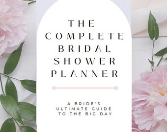 May include: A white bridal shower planner with the text "THE COMPLETE BRIDAL SHOWER PLANNER" and "A BRIDE'S ULTIMATE GUIDE TO THE BIG DAY." The planner is surrounded by pink flowers and green leaves.