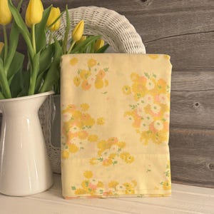 May include: A yellow floral patterned fabric sheet with a white background. The fabric has a small floral pattern with yellow, pink, and green flowers.