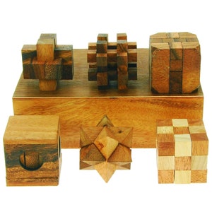 May include: Six wooden brain teaser puzzles in various shapes and sizes, including a cube, a star, and a cross. The puzzles are arranged on a wooden base.