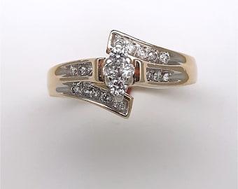 May include: A gold ring with a pear-shaped diamond center stone and smaller diamonds set in the band.