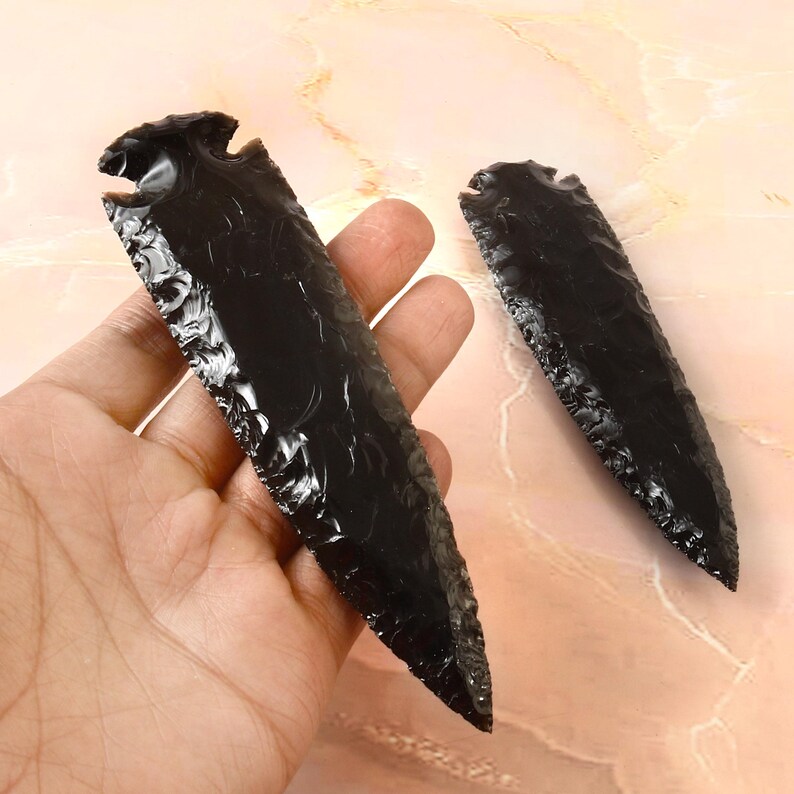 May include: Two black obsidian arrowheads with a pointed tip and a textured surface.